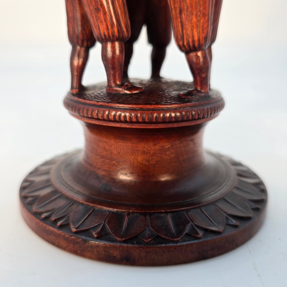A tall hand-carved dark walnut lidded chalice featuring a stem sculpted as human figures, a relief carving of cattle around the vessel, and a finial with carved figures. View XV