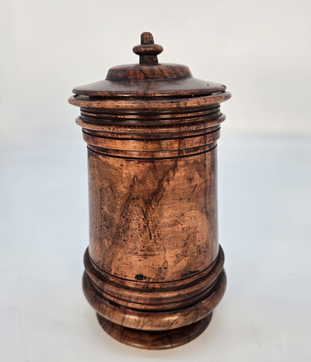 An 18th-century turned walnut wooden tobacco jar featuring a knopped finial lid, turned mouldings, and a dark aged grain surface. View III