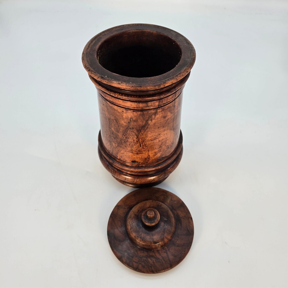 An 18th-century turned walnut wooden tobacco jar featuring a knopped finial lid, turned mouldings, and a dark aged grain surface. View V