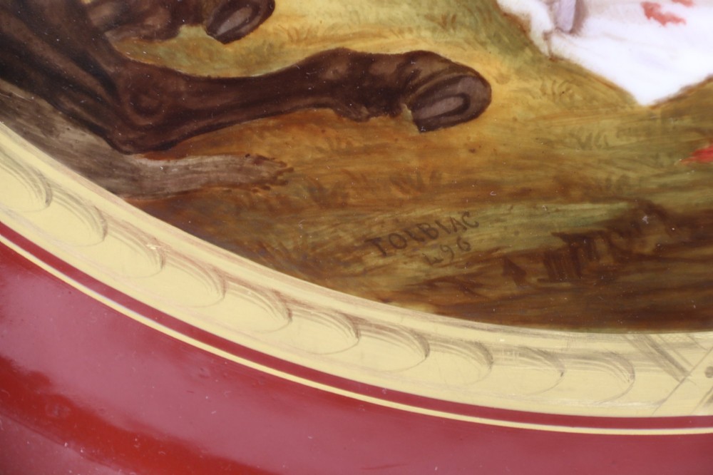 A large round porcelain charger with a deep burgundy border edged in gold leaf, featuring a central hand-painted scene depicting a historic battle with figures on horseback. View II