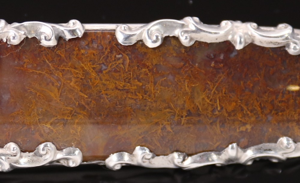 An elongated Georgian silver bar brooch featuring a rectangular polished moss agate panel with a scrollwork silver border. View III