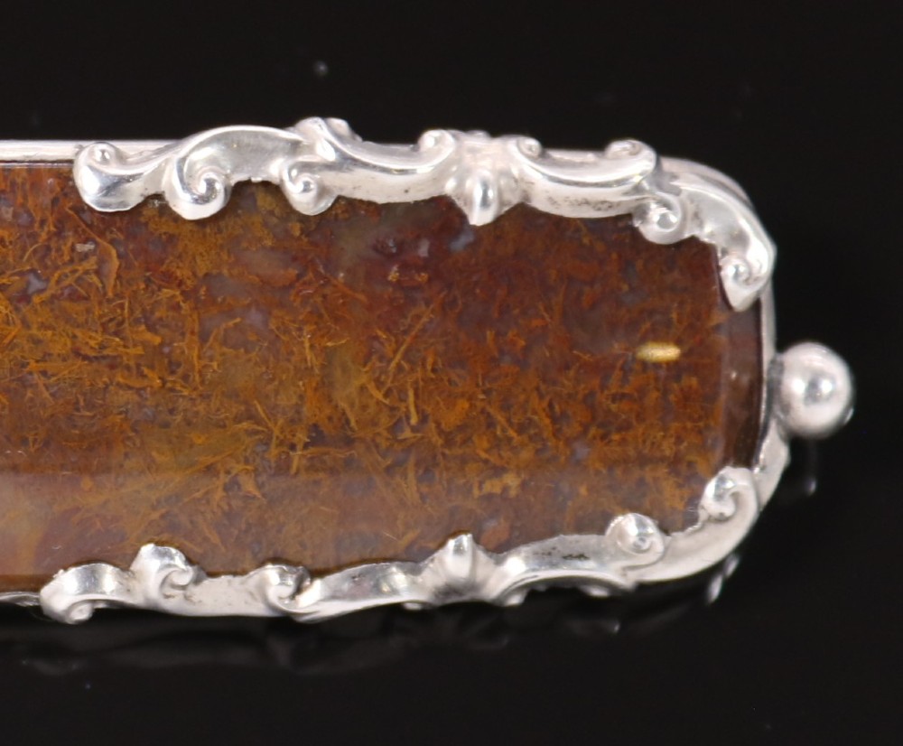 An elongated Georgian silver bar brooch featuring a rectangular polished moss agate panel with a scrollwork silver border. View IV