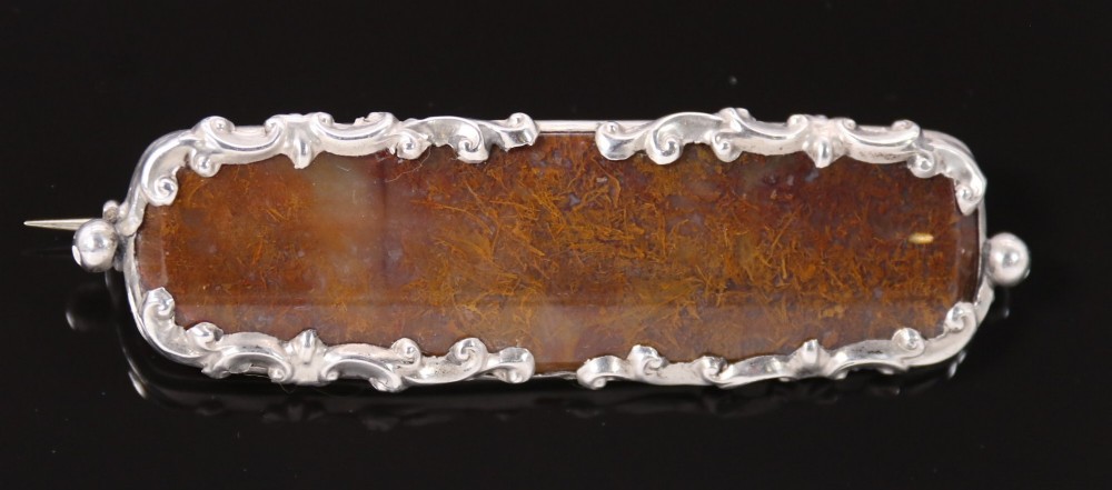 An elongated Georgian silver bar brooch featuring a rectangular polished moss agate panel with a scrollwork silver border. View V