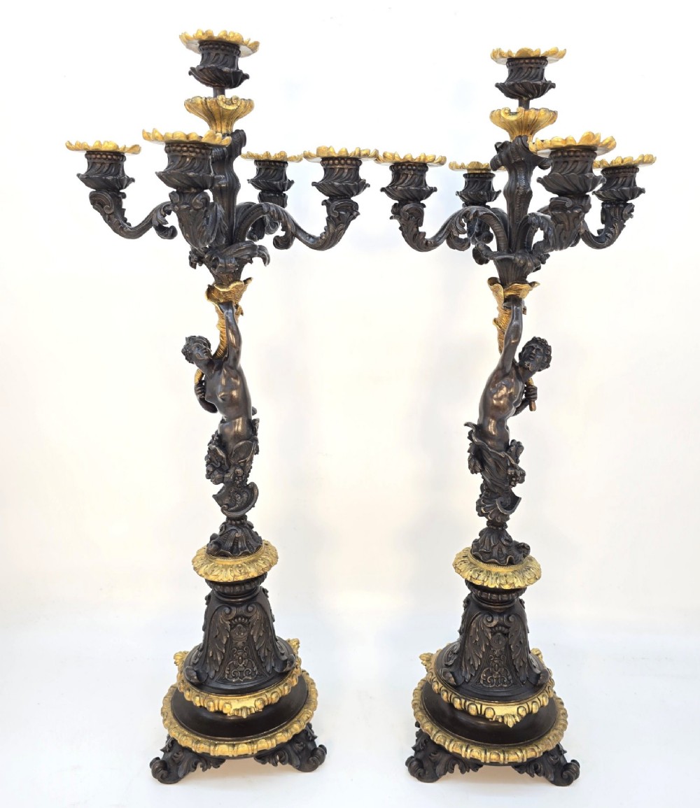 A pair of 19th-century French dark patinated bronze five-light candelabra with gilt bronze accents and sculptural figures.