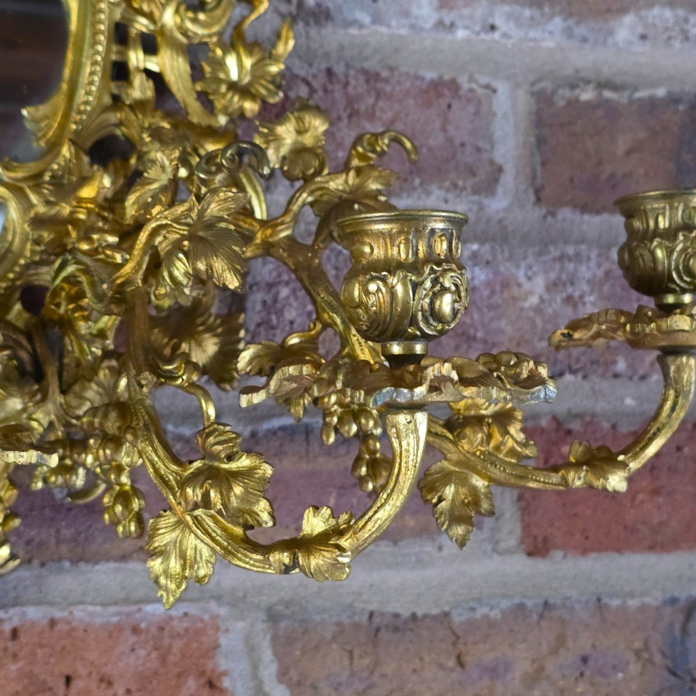 A 19th-century French ormolu girandole wall mirror featuring an ornate foliage frame, central oval mirror, and six branching candle arms. View V