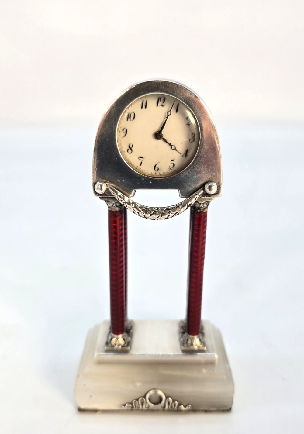 A Viennese silver and red guilloche enamel miniature portico desk clock mounted on a white onyx base. View II