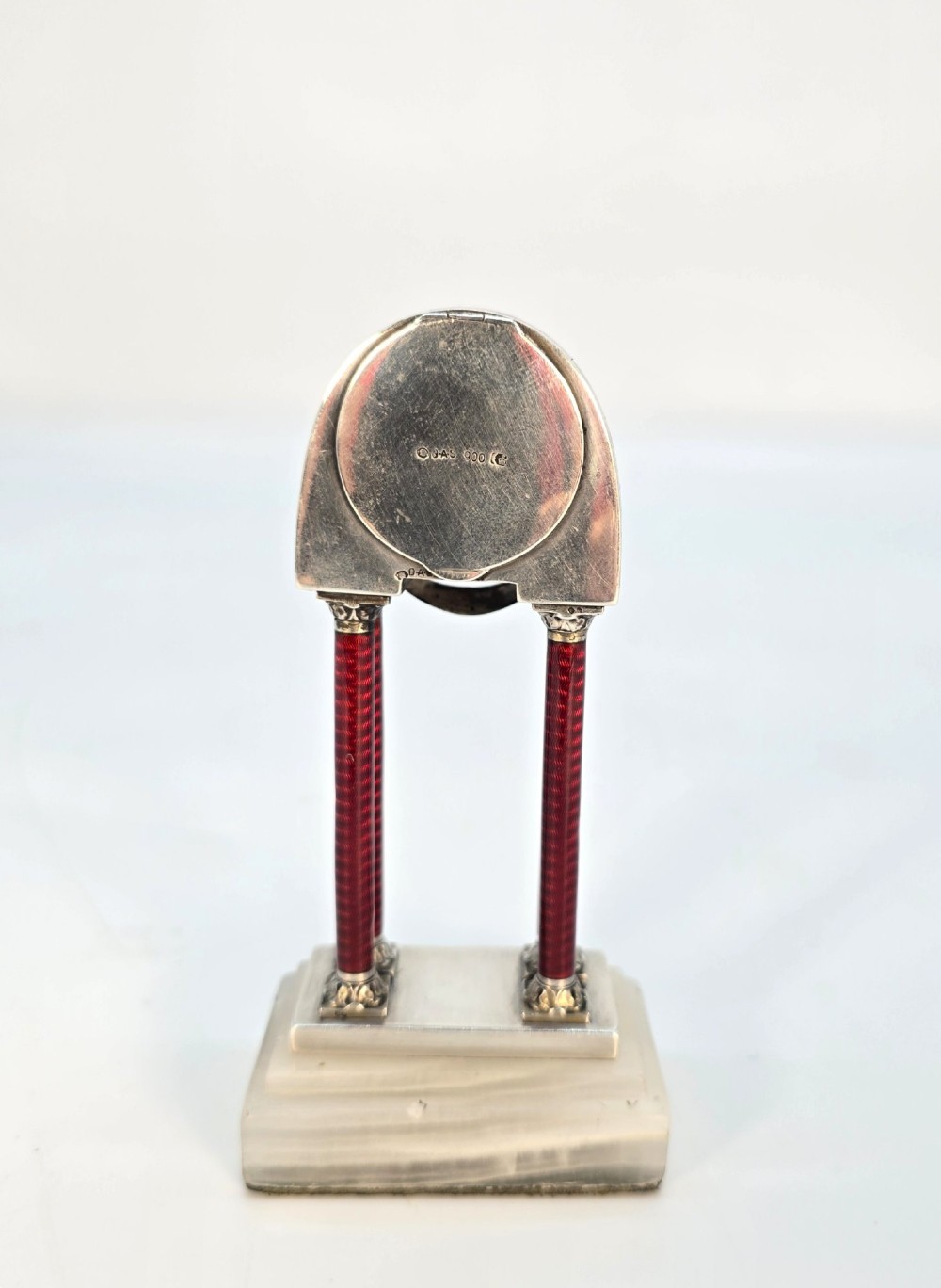 A Viennese silver and red guilloche enamel miniature portico desk clock mounted on a white onyx base. View VI
