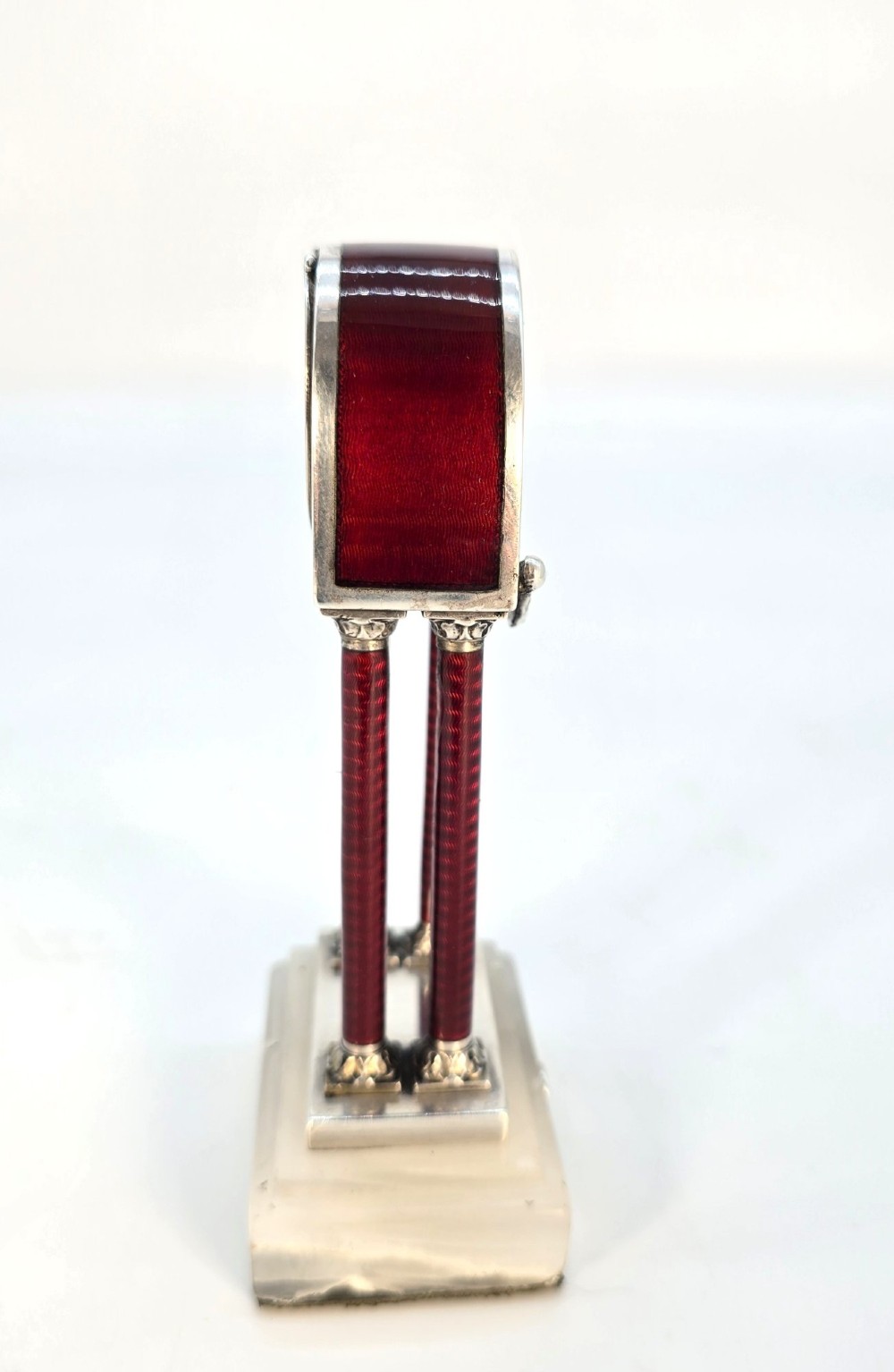 A Viennese silver and red guilloche enamel miniature portico desk clock mounted on a white onyx base. View VIII