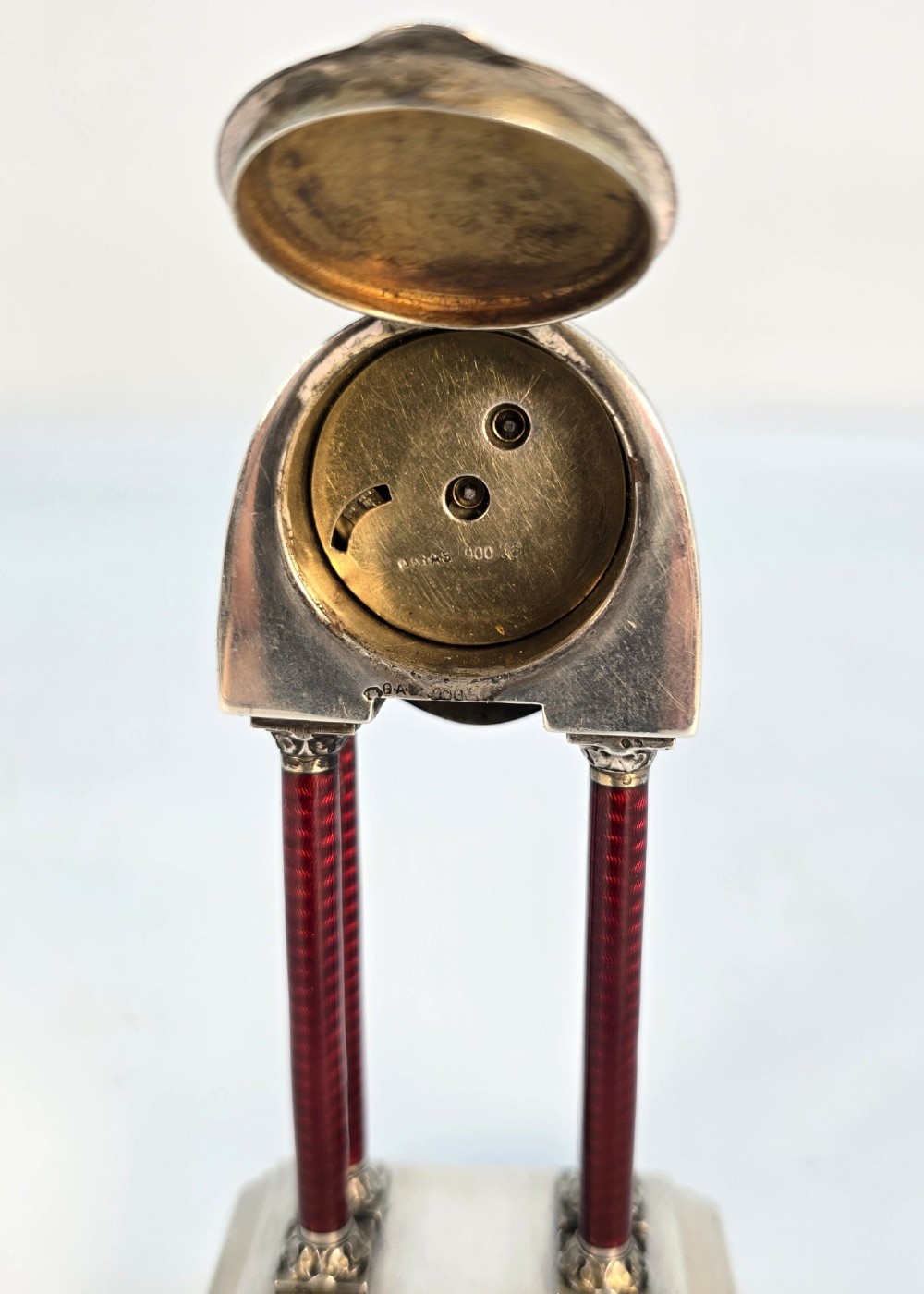 A Viennese silver and red guilloche enamel miniature portico desk clock mounted on a white onyx base. View X