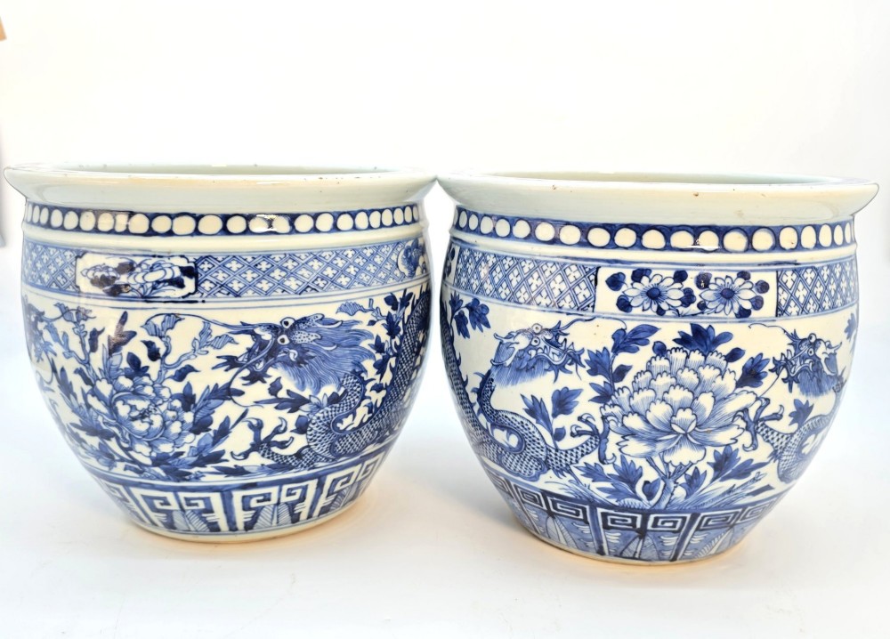 A pair of rounded Chinese porcelain jardinieres decorated with underglaze cobalt blue dragon and floral motifs.