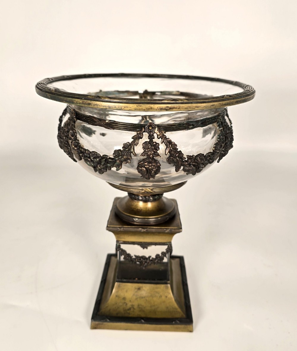 A clear glass bowl mounted with gilt-bronze floral swags and supported by a square stepped pedestal base. View V