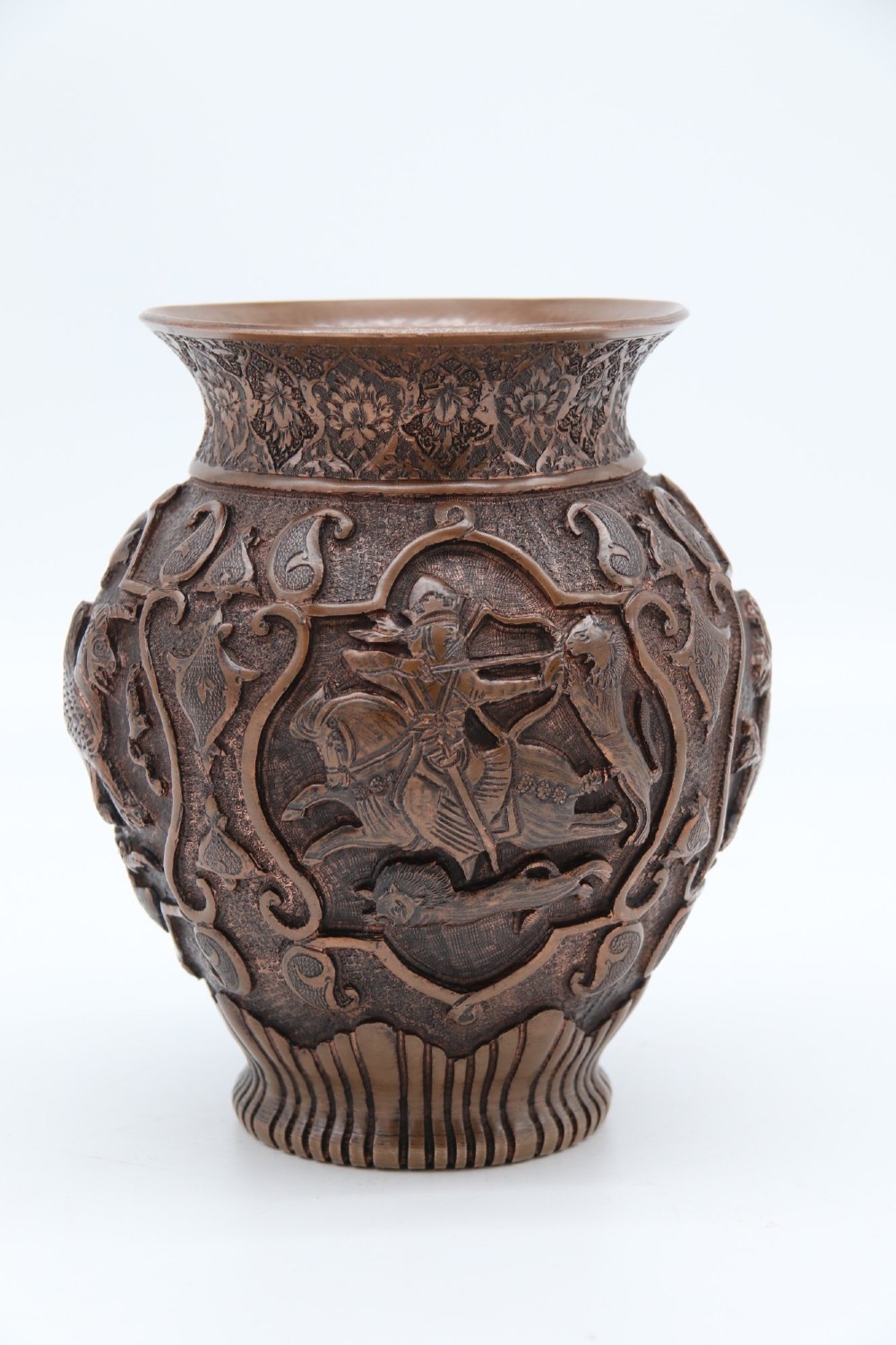 A bulbous late nineteenth-century copper vase featuring detailed repousse carvings of a mounted archer within a central cartouche surrounded by scrollwork and a fluted base.
