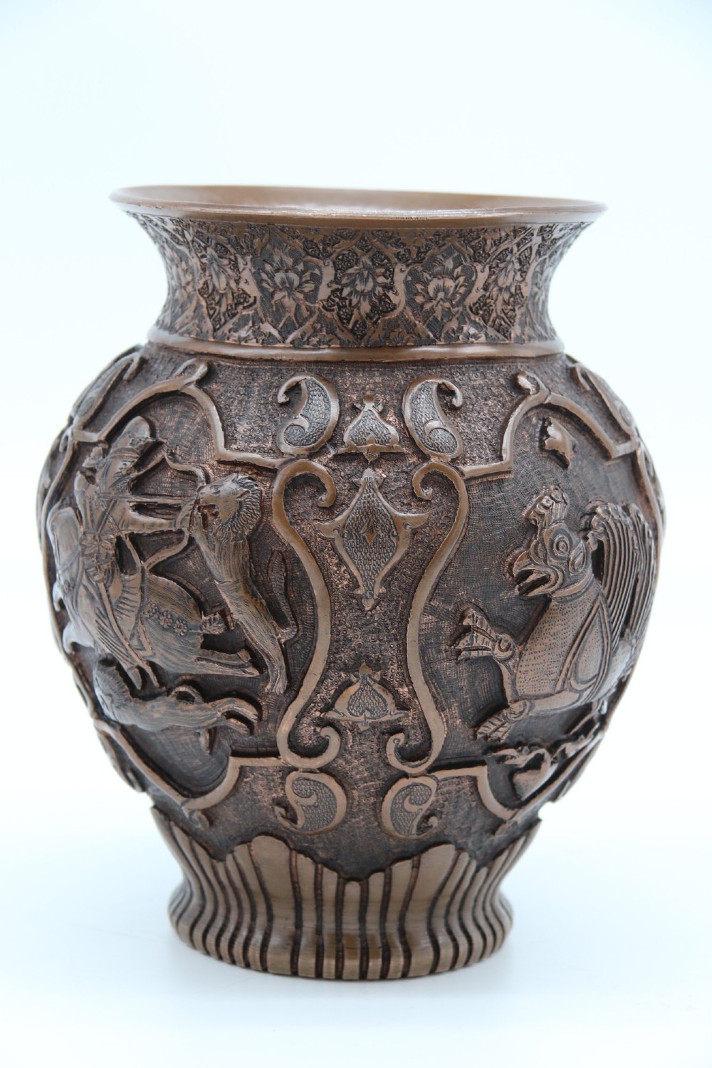 A bulbous late nineteenth-century copper vase featuring detailed repousse carvings of a mounted archer within a central cartouche surrounded by scrollwork and a fluted base. View II