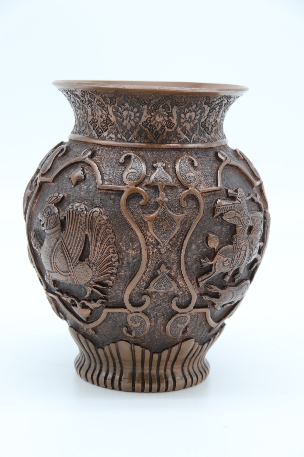 A bulbous late nineteenth-century copper vase featuring detailed repousse carvings of a mounted archer within a central cartouche surrounded by scrollwork and a fluted base. View IV
