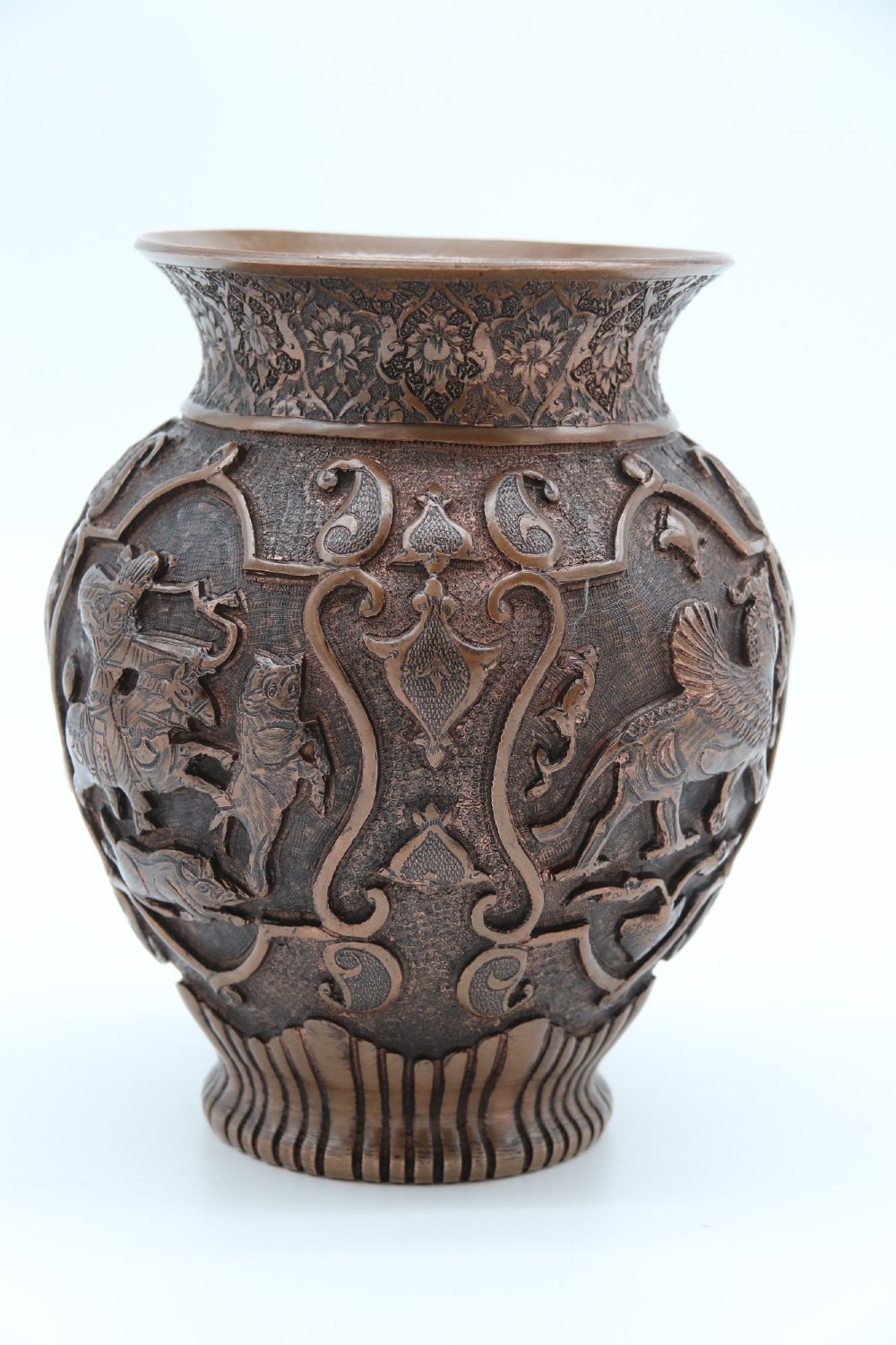 A bulbous late nineteenth-century copper vase featuring detailed repousse carvings of a mounted archer within a central cartouche surrounded by scrollwork and a fluted base. View VI