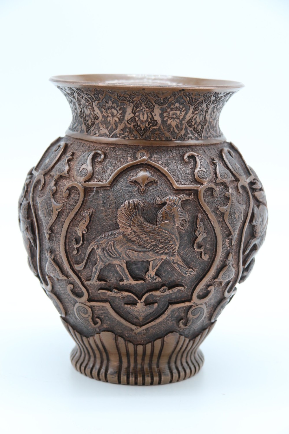 A bulbous late nineteenth-century copper vase featuring detailed repousse carvings of a mounted archer within a central cartouche surrounded by scrollwork and a fluted base. View VII