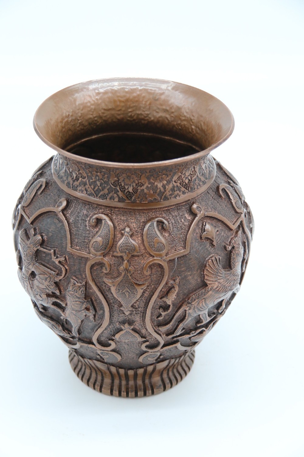 A bulbous late nineteenth-century copper vase featuring detailed repousse carvings of a mounted archer within a central cartouche surrounded by scrollwork and a fluted base. View IX