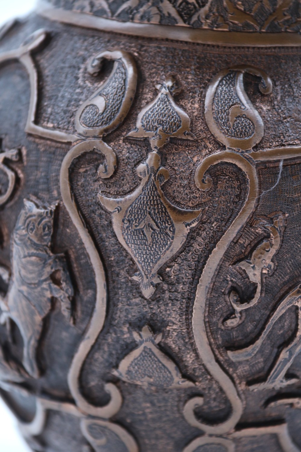 A bulbous late nineteenth-century copper vase featuring detailed repousse carvings of a mounted archer within a central cartouche surrounded by scrollwork and a fluted base. View X