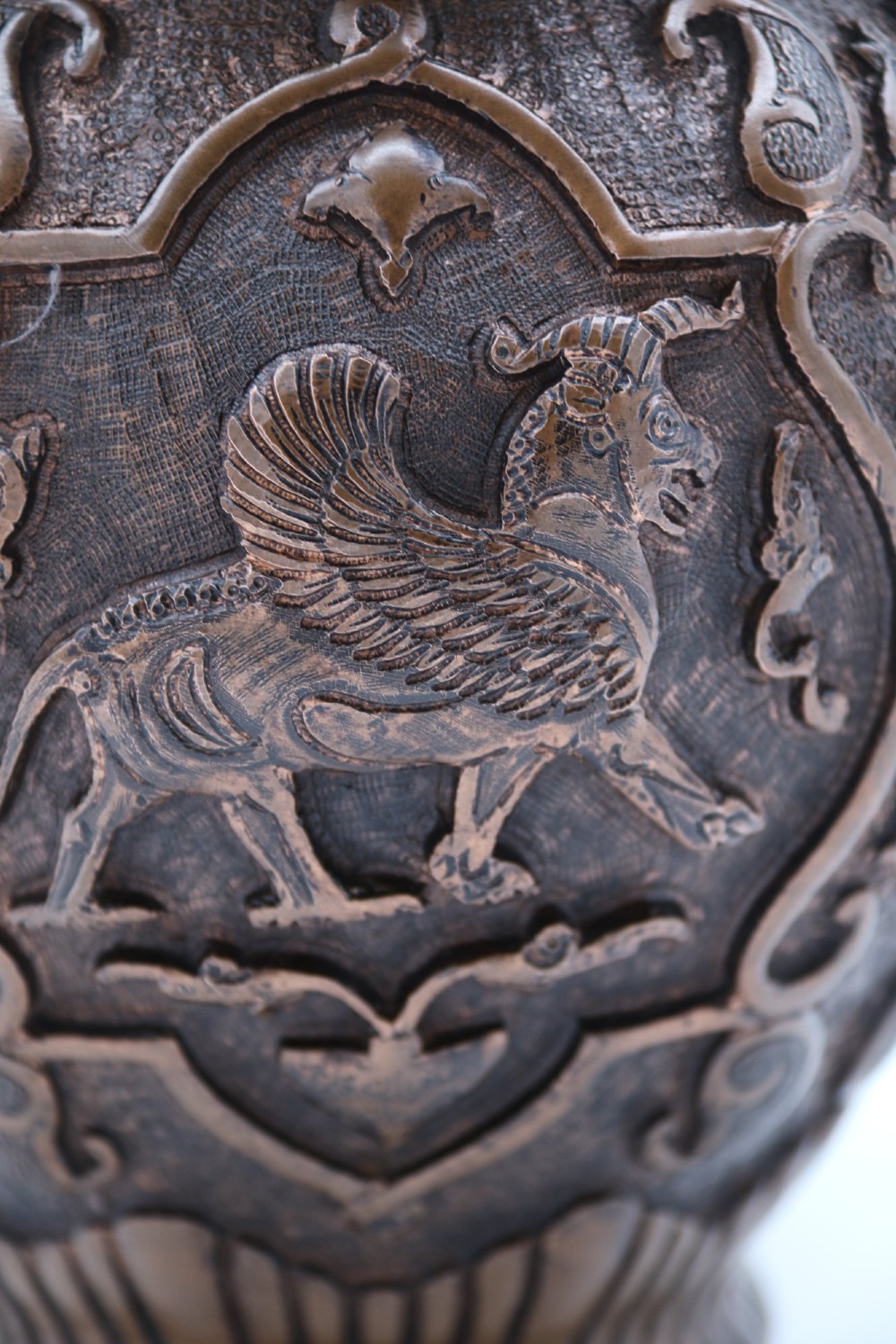 A bulbous late nineteenth-century copper vase featuring detailed repousse carvings of a mounted archer within a central cartouche surrounded by scrollwork and a fluted base. View XI
