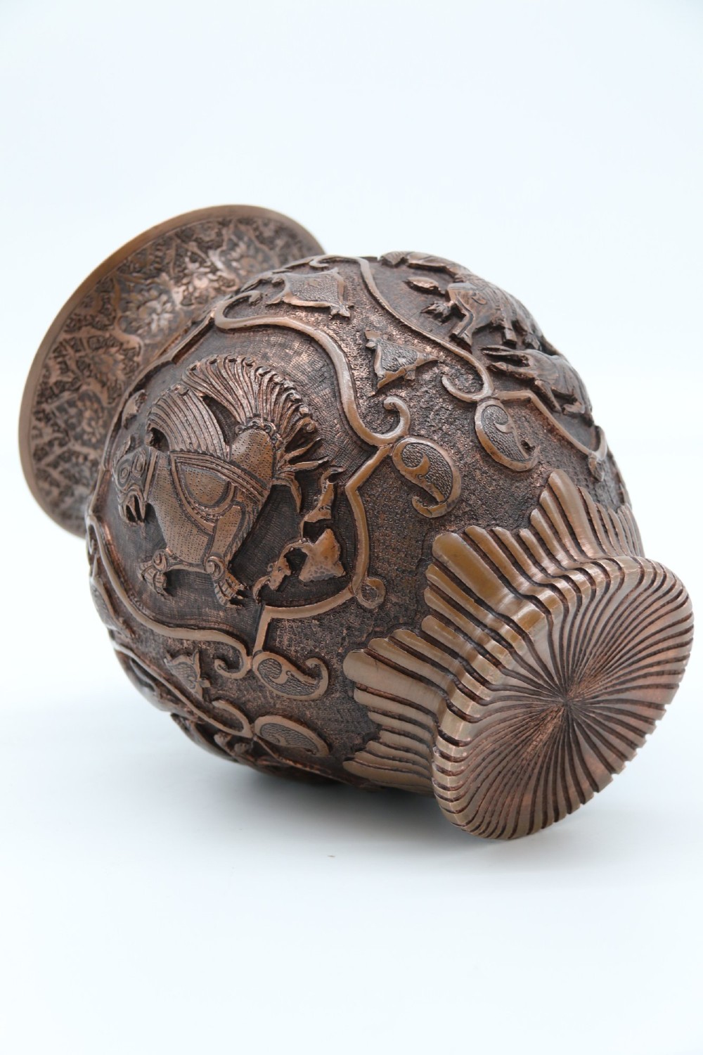 A bulbous late nineteenth-century copper vase featuring detailed repousse carvings of a mounted archer within a central cartouche surrounded by scrollwork and a fluted base. View XV