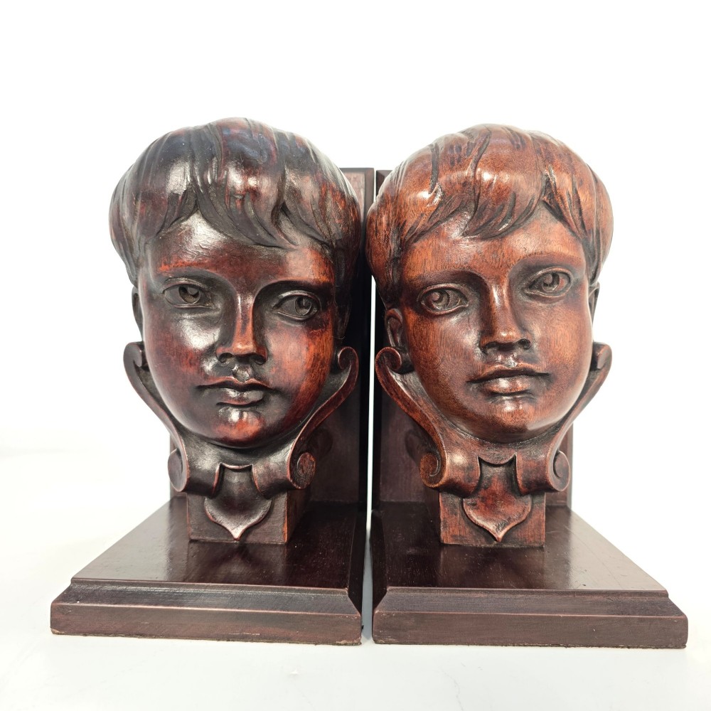 A pair of carved mahogany bookends depicting the profile busts of choir boys mounted on L-shaped wooden bases. View IV