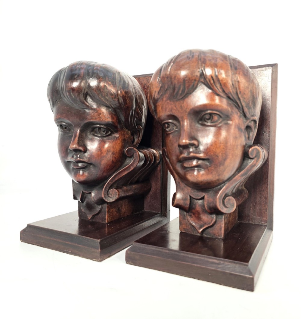 A pair of carved mahogany bookends depicting the profile busts of choir boys mounted on L-shaped wooden bases. View VI