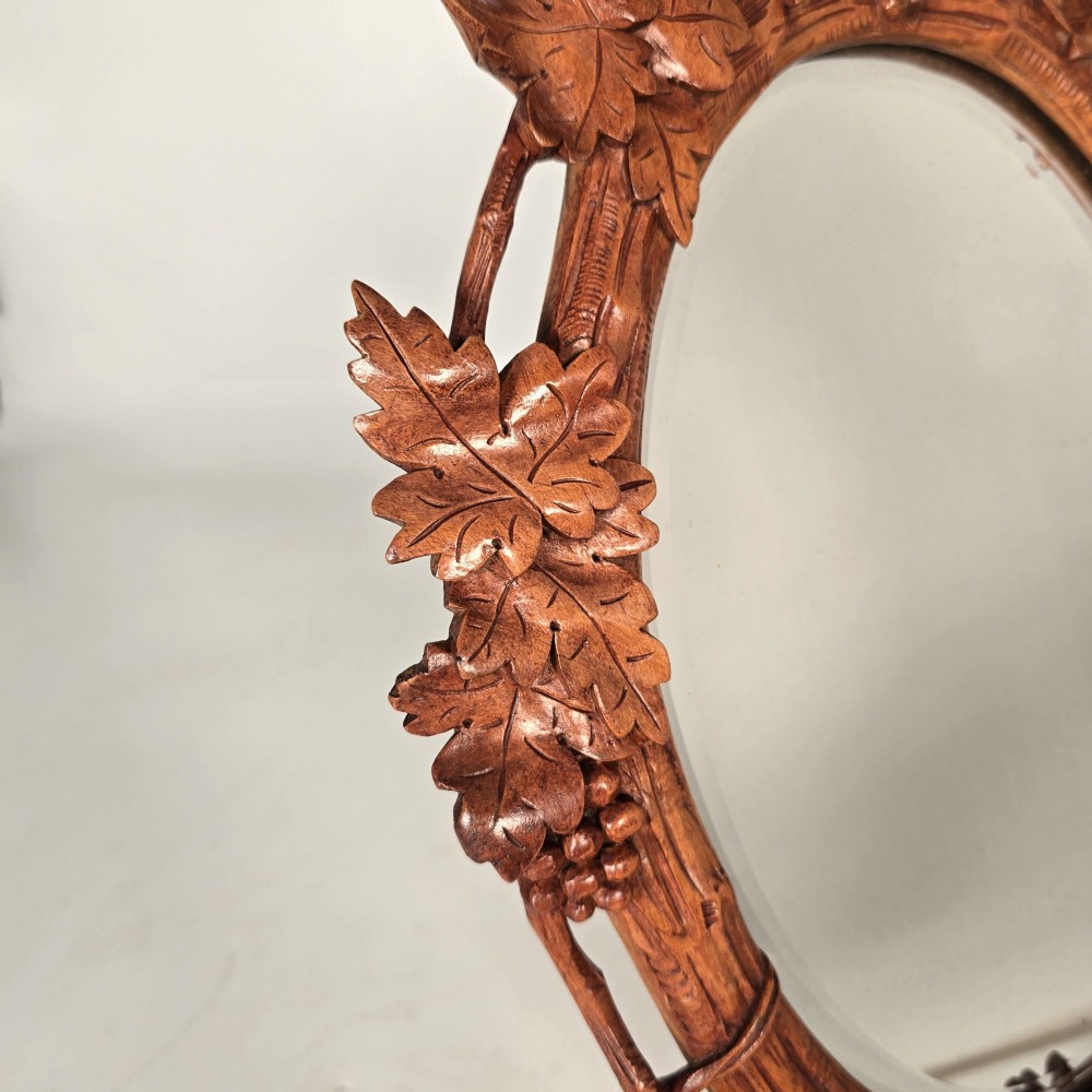 A late nineteenth-century Swiss carved lime wood oval table mirror surrounded by relief carvings of grapevine leaves and grapes. View II