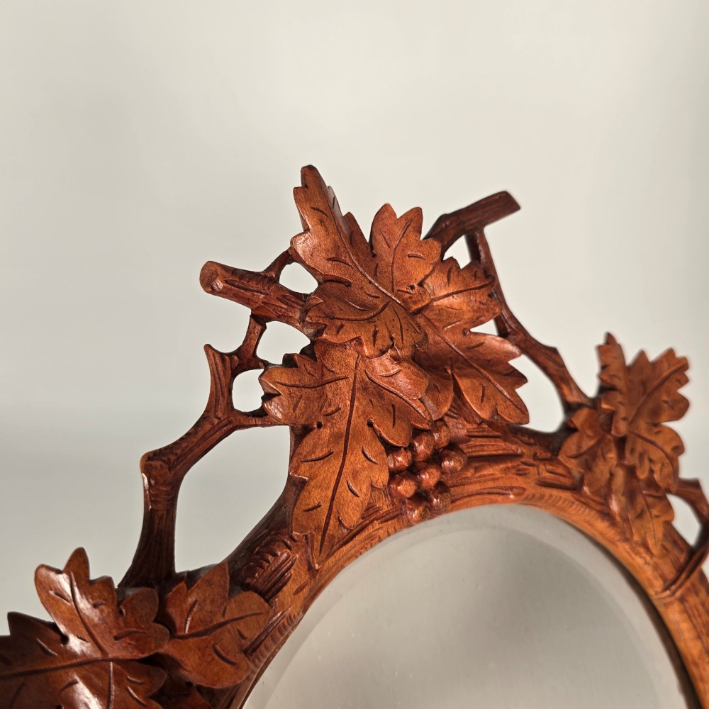 A late nineteenth-century Swiss carved lime wood oval table mirror surrounded by relief carvings of grapevine leaves and grapes. View III