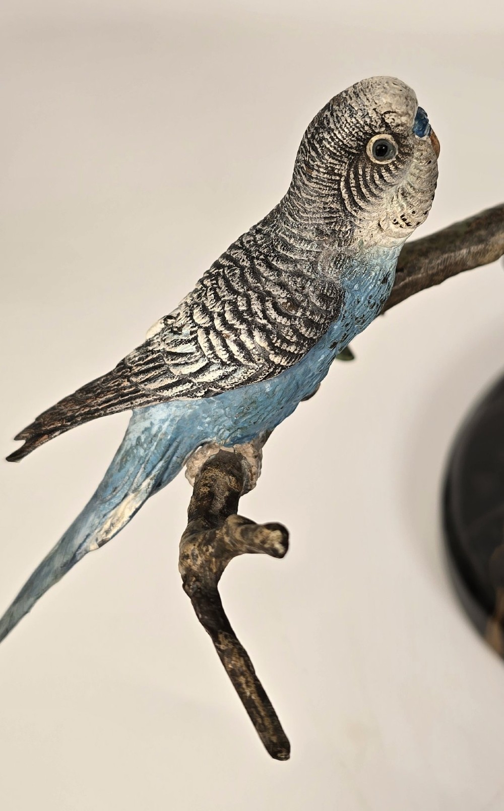 A cold-painted bronze sculpture featuring three blue and grey budgerigars perched on a leafy bronze branch, mounted on an oval dark marble base. View X