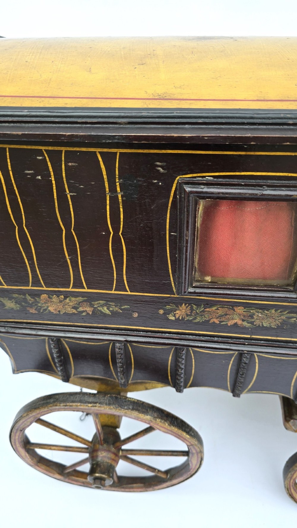 Hand-painted Edwardian wooden scale model of a Romani vardo caravan in dark brown and yellow with floral motifs and spoked wheels. View IX