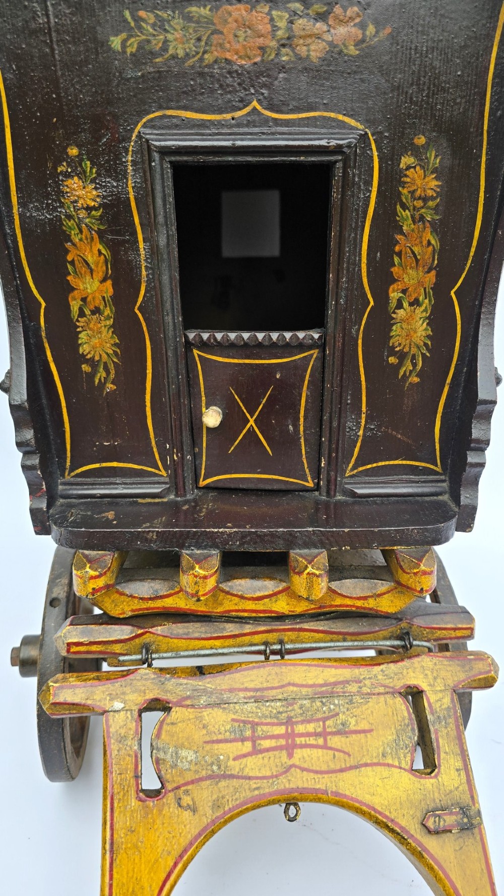 Hand-painted Edwardian wooden scale model of a Romani vardo caravan in dark brown and yellow with floral motifs and spoked wheels. View XII