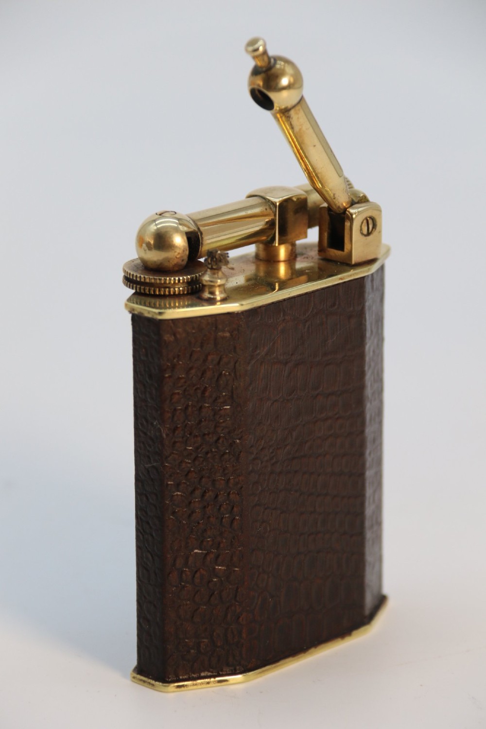 An Art Deco French table lighter featuring a textured brown leather-wrapped faceted body and a polished brass lift-arm ignition mechanism. View VII
