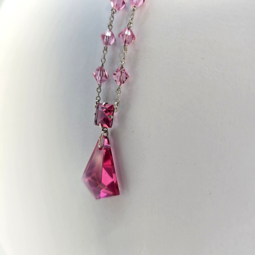 An Art Deco style silver chain necklace featuring faceted pink crystal bicone beads and a geometric triangular crystal pendant drop. View IV