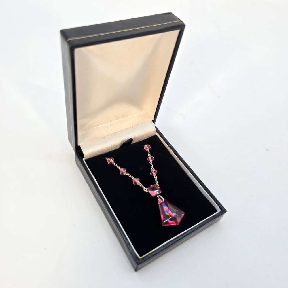 An Art Deco style silver chain necklace featuring faceted pink crystal bicone beads and a geometric triangular crystal pendant drop. View VII