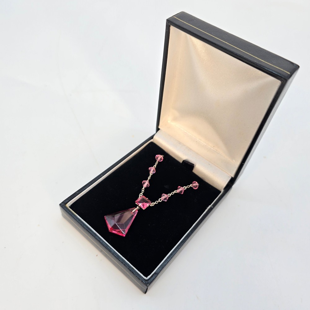 An Art Deco style silver chain necklace featuring faceted pink crystal bicone beads and a geometric triangular crystal pendant drop. View VIII