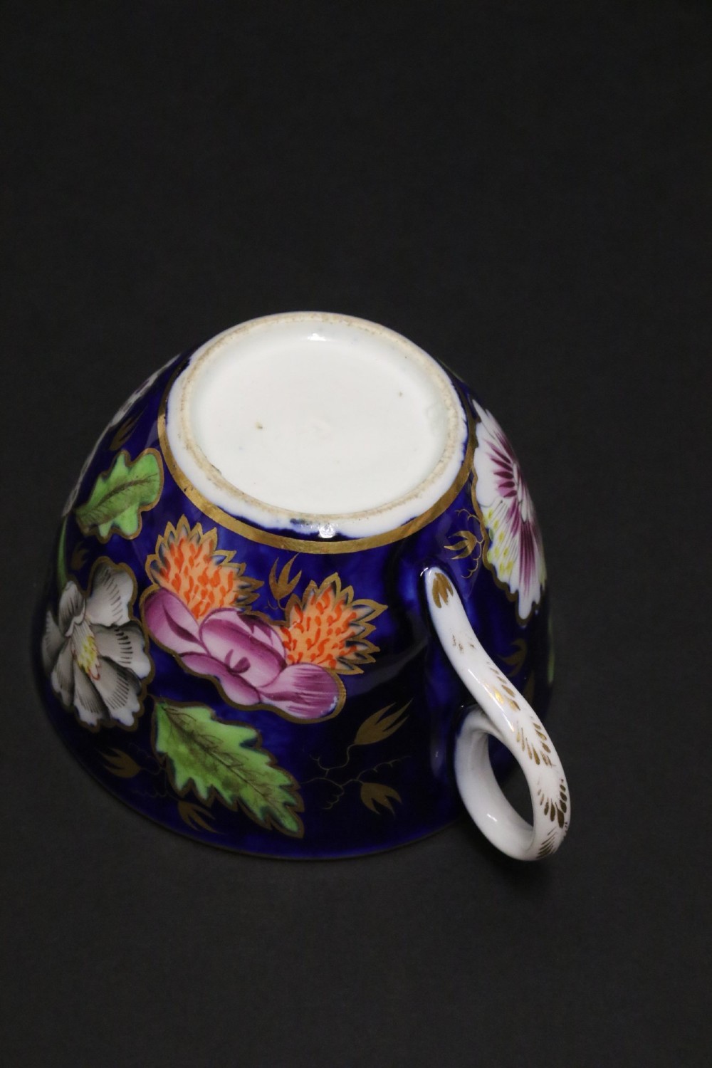 An early 19th-century English Newhall porcelain cabinet trio with a cobalt blue ground, hand-painted botanical flowers, and gilded borders. View XI