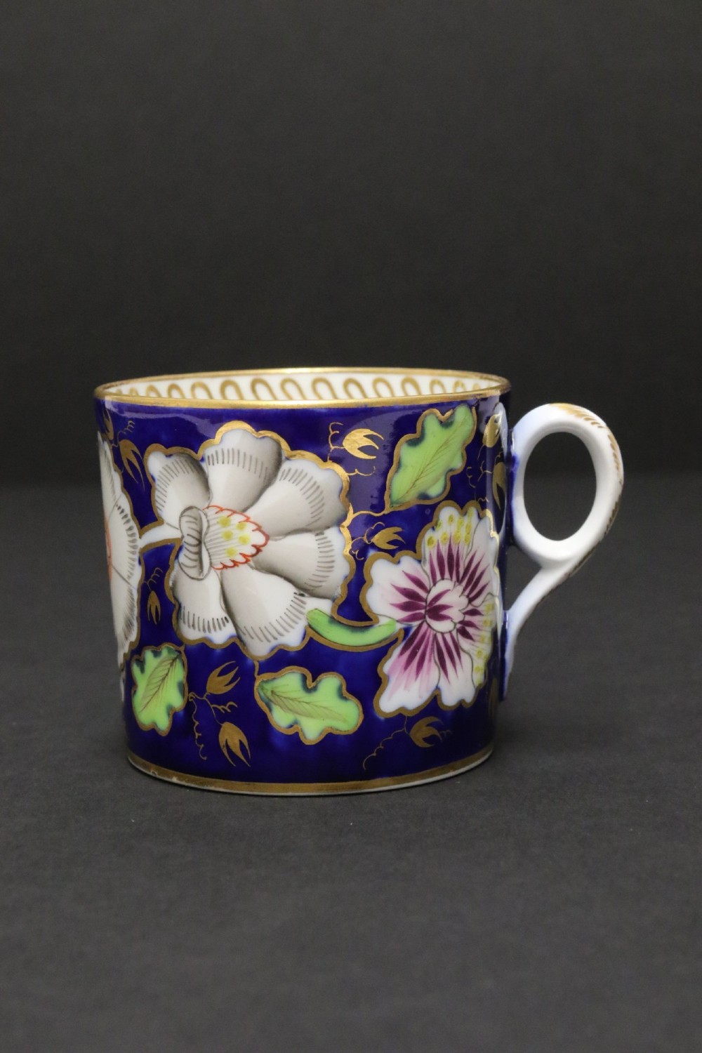 An early 19th-century English Newhall porcelain cabinet trio with a cobalt blue ground, hand-painted botanical flowers, and gilded borders. View XII