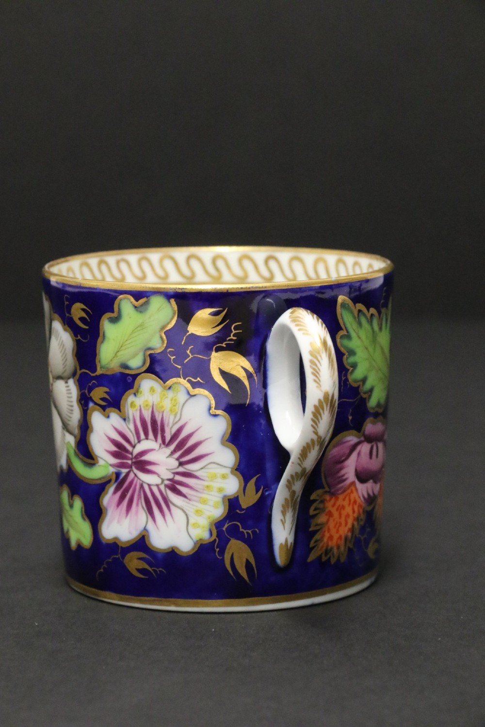 An early 19th-century English Newhall porcelain cabinet trio with a cobalt blue ground, hand-painted botanical flowers, and gilded borders. View XIII