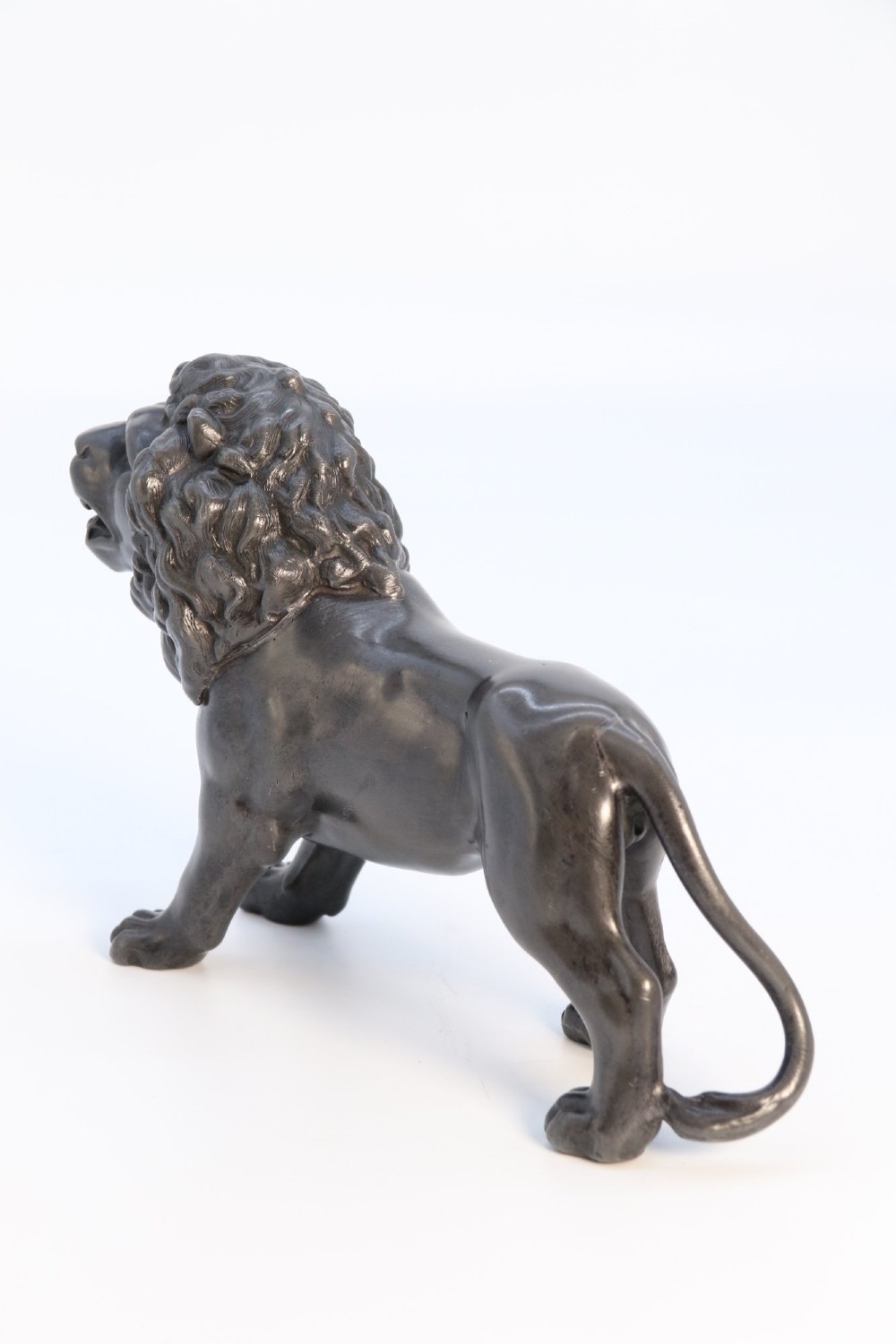 A dark patinated pewter sculpture depicting a standing male lion with a flowing mane and open mouth. View V