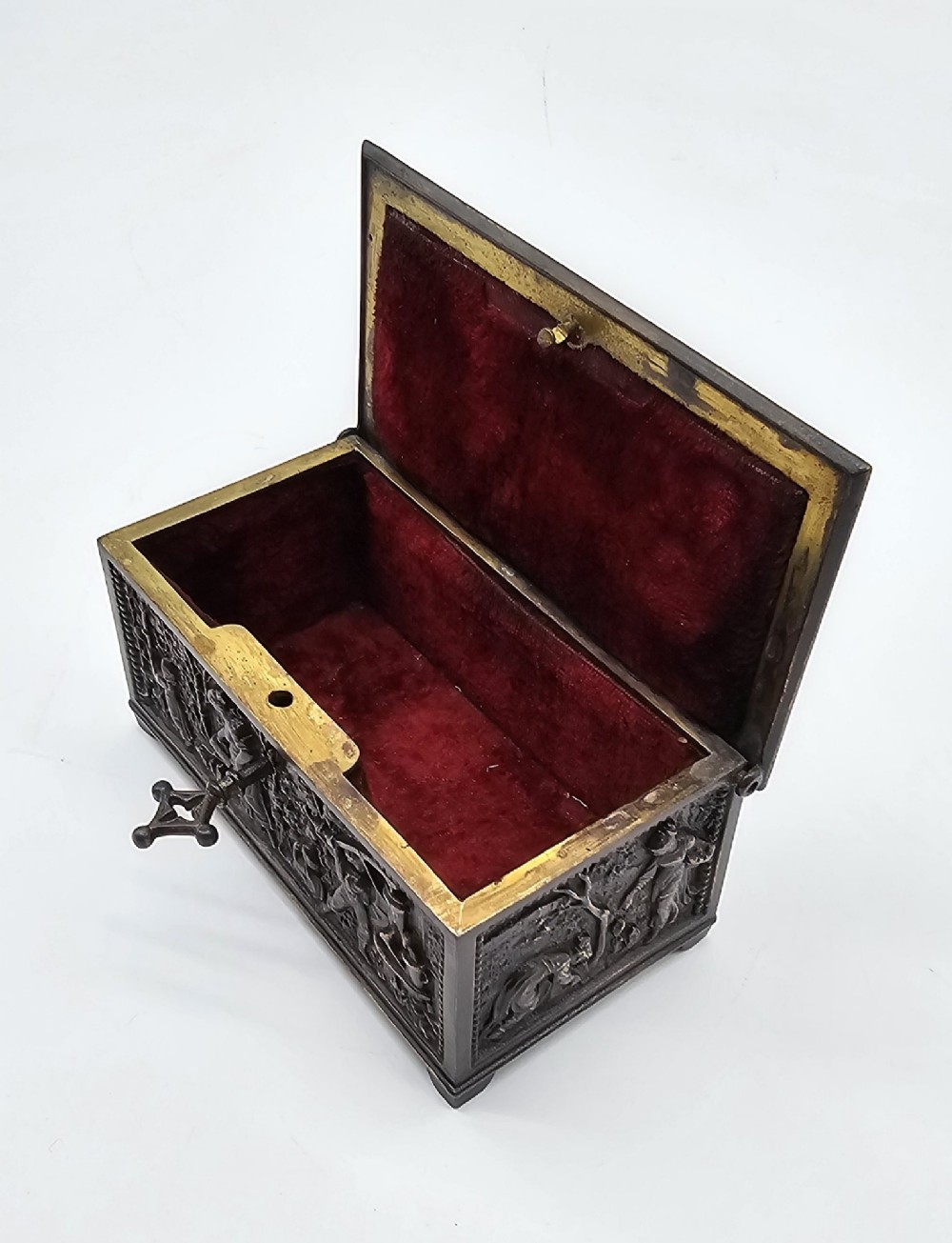 A dark patinated bronze rectangular jewellery casket featuring raised relief scenes of horses on the lid and rural figures on the side, displayed with its key. View IV