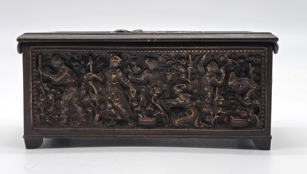 A dark patinated bronze rectangular jewellery casket featuring raised relief scenes of horses on the lid and rural figures on the side, displayed with its key. View IX