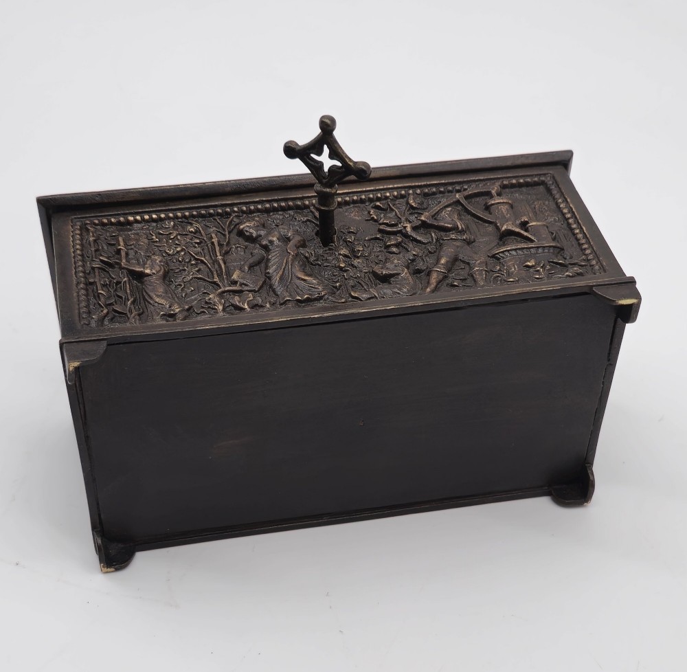 A dark patinated bronze rectangular jewellery casket featuring raised relief scenes of horses on the lid and rural figures on the side, displayed with its key. View XIV
