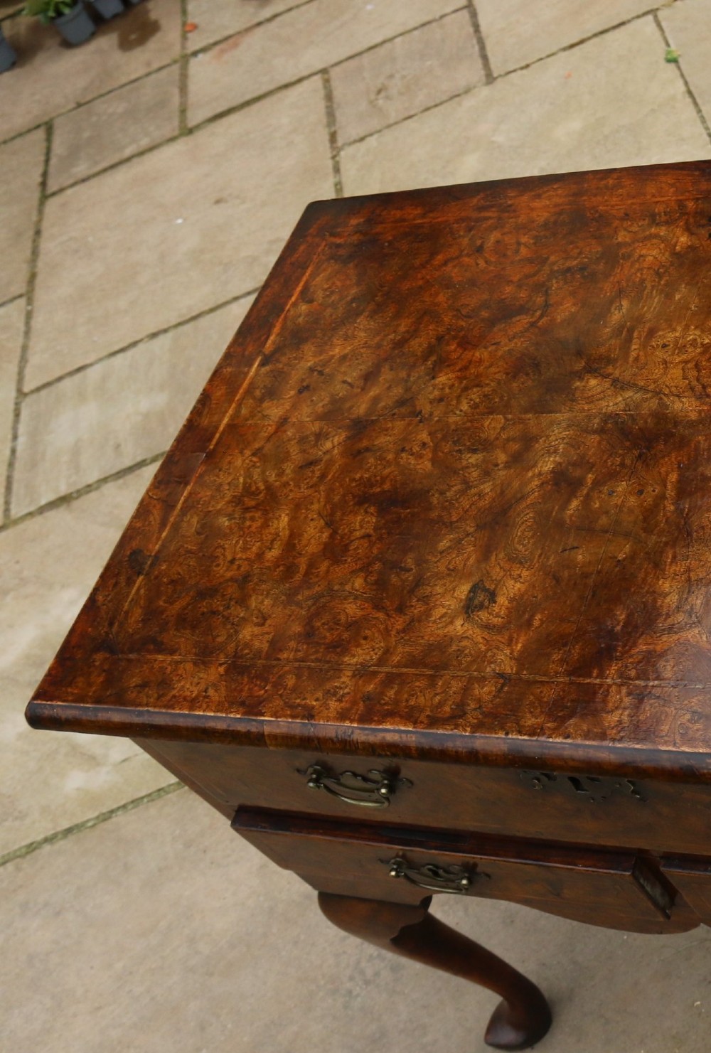 A George II burr elm lowboy table with three drawers, brass handles, a shaped apron, and cabriole legs. View IX