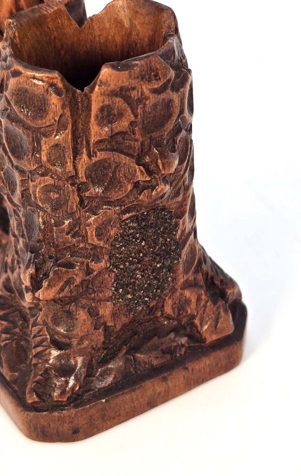 A carved brown limewood match holder depicting a hooded bearded gnome standing beside a textured tree stump container. View XIV