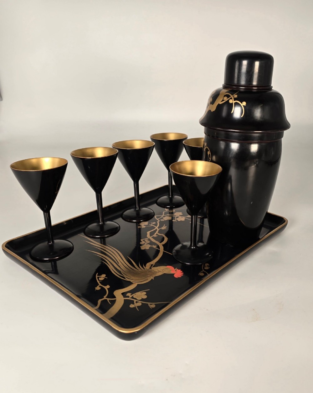 A black and gold hand-painted Japanese lacquer cocktail set comprising a shaker, six stemmed glasses, and a rectangular tray adorned with rooster motifs. View XV
