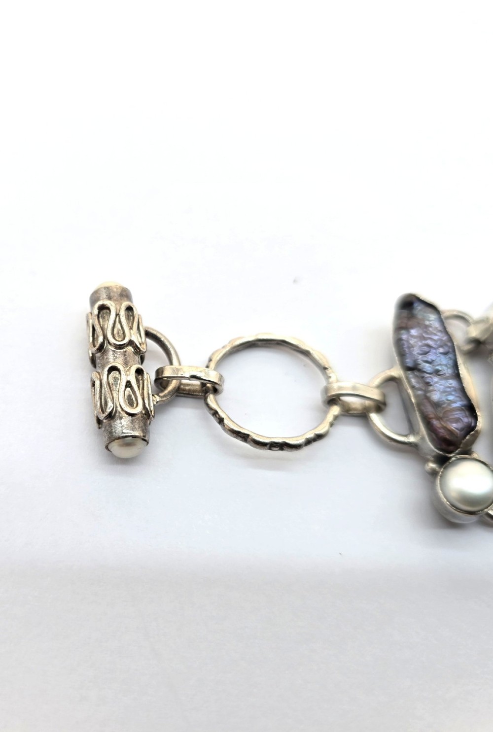 A 1960s Japanese silver jewellery set featuring an articulated link bracelet and a matching ring set with elongated, iridescent Biwa pearls and round white pearls. View V