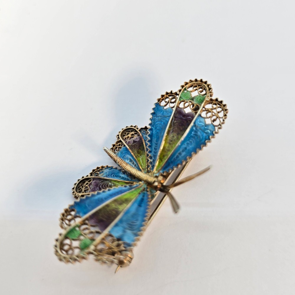 An Art Deco silver gilt butterfly brooch featuring blue, green, and purple enamel panels edged with wire filigree. View IV