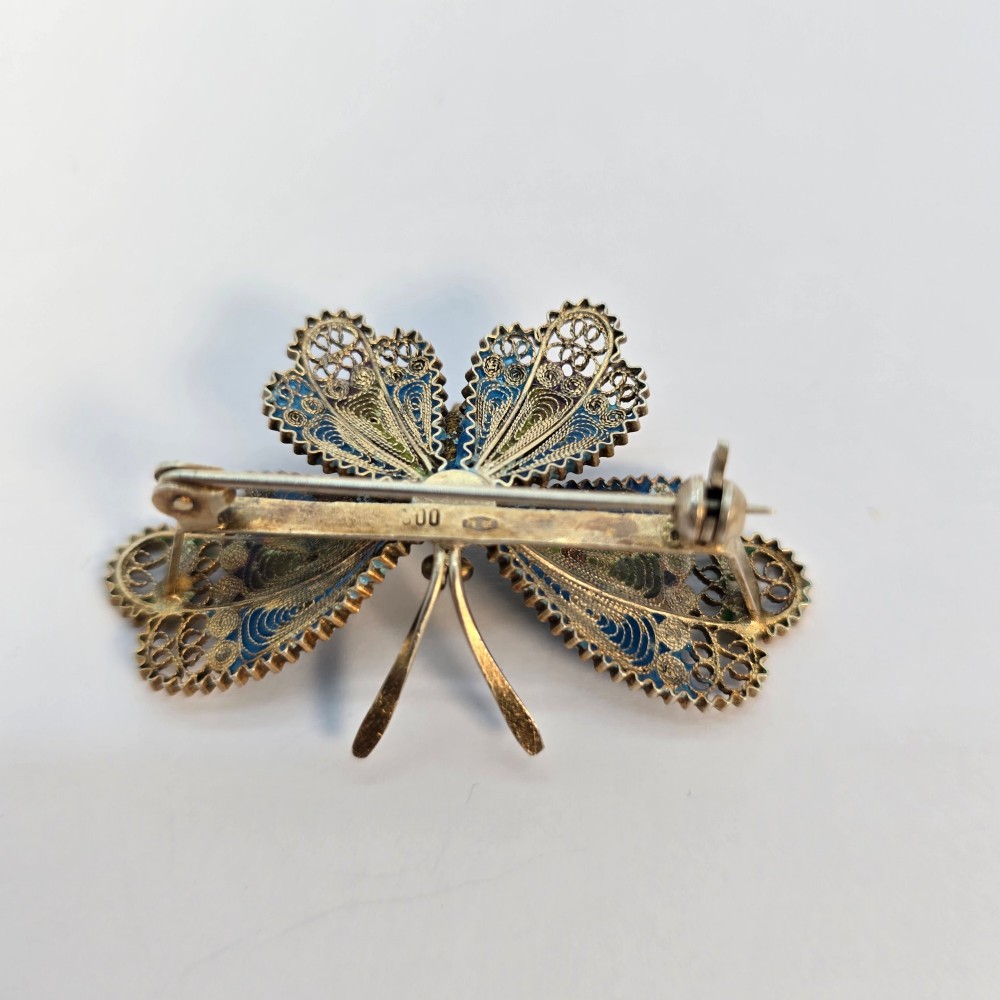 An Art Deco silver gilt butterfly brooch featuring blue, green, and purple enamel panels edged with wire filigree. View VII