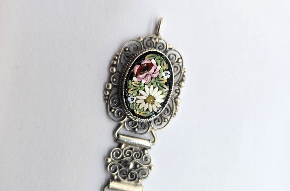 An Italian silver filigree link bracelet featuring oval micro mosaic panels with floral motifs set against a dark background. View V
