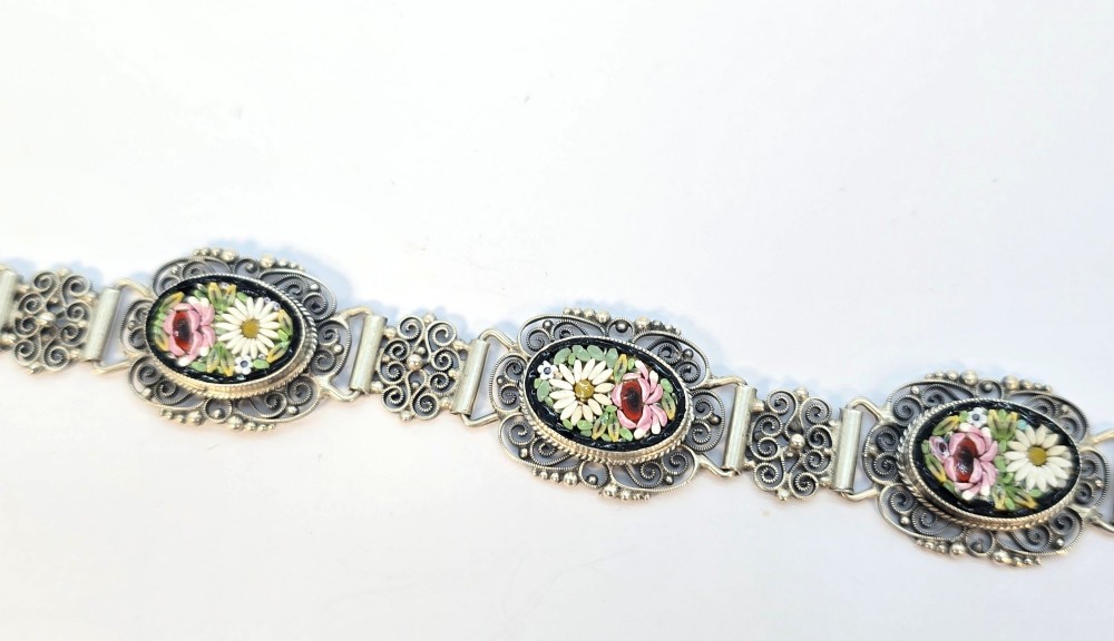 An Italian silver filigree link bracelet featuring oval micro mosaic panels with floral motifs set against a dark background. View VI